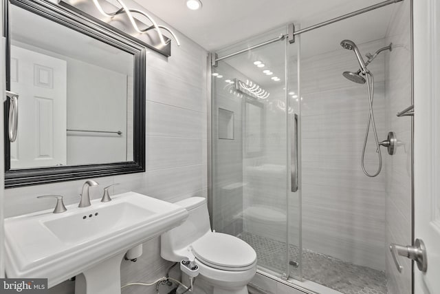 bathroom with tile walls, sink, an enclosed shower, and toilet