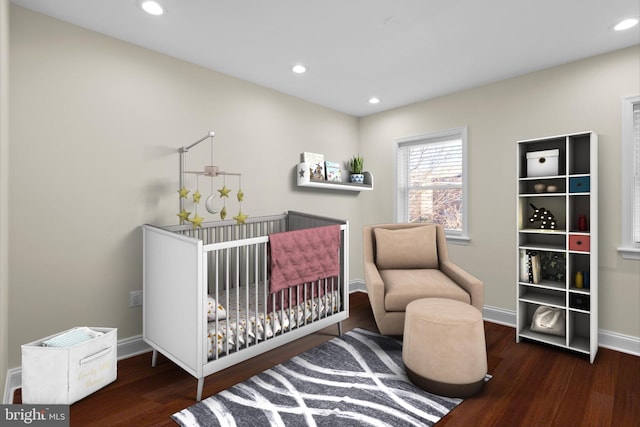 bedroom featuring a crib and dark wood-type flooring