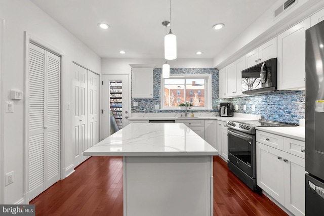 kitchen featuring white cabinets, appliances with stainless steel finishes, a center island, and hanging light fixtures