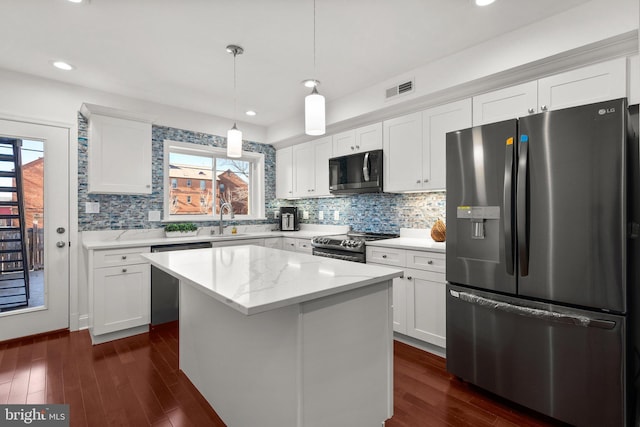 kitchen featuring stainless steel appliances, sink, pendant lighting, a center island, and white cabinetry