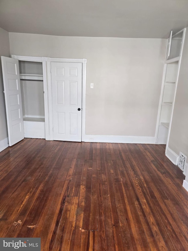 unfurnished bedroom featuring dark hardwood / wood-style flooring and a closet