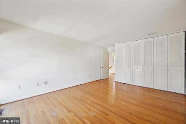 unfurnished bedroom featuring light wood-style floors, a closet, and visible vents