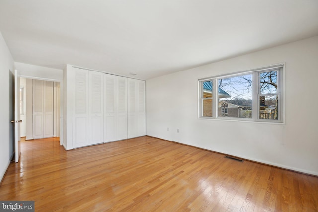 unfurnished bedroom featuring light wood-style flooring, visible vents, and a closet