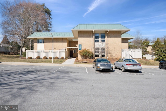 view of building exterior with uncovered parking and fence