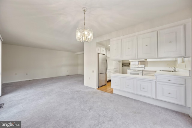 kitchen featuring white electric range, light countertops, freestanding refrigerator, open floor plan, and a sink