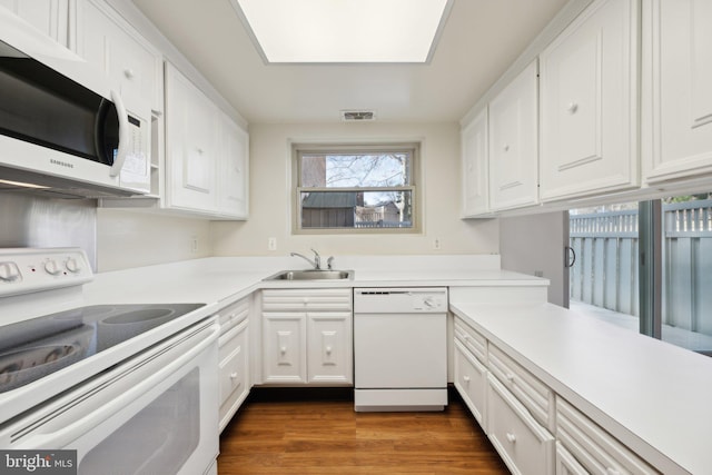 kitchen featuring light countertops, white appliances, a sink, and white cabinetry