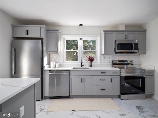 kitchen with sink, light stone counters, backsplash, decorative light fixtures, and appliances with stainless steel finishes