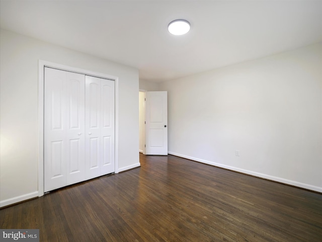 unfurnished bedroom with dark wood-type flooring and a closet