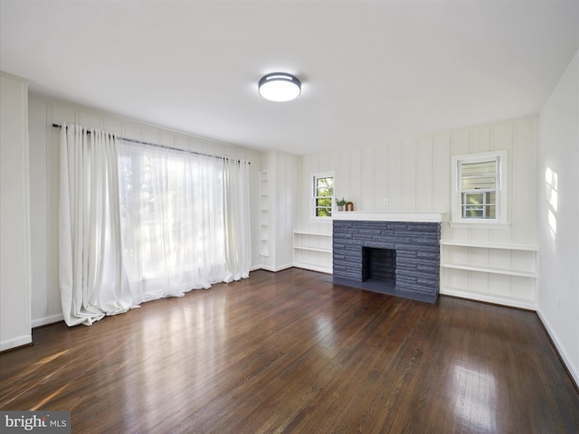 unfurnished living room featuring a fireplace, dark hardwood / wood-style floors, and a wealth of natural light