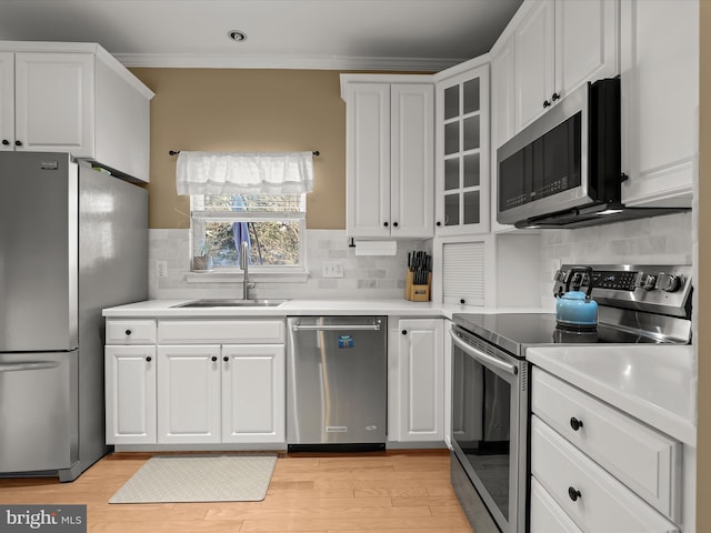 kitchen with tasteful backsplash, white cabinetry, sink, and stainless steel appliances