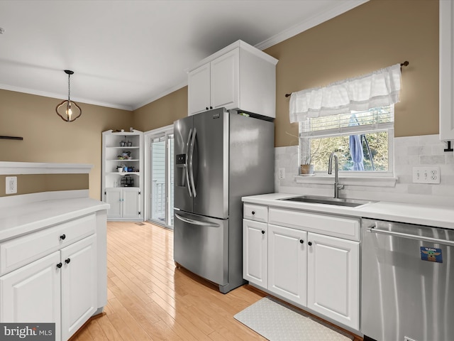 kitchen featuring white cabinets, decorative light fixtures, sink, and appliances with stainless steel finishes