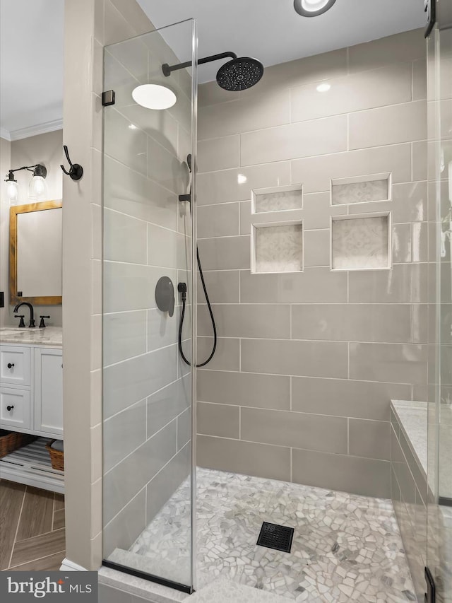 bathroom with vanity, a shower with shower door, and ornamental molding