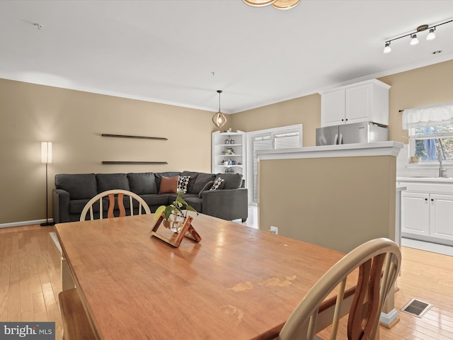 dining space featuring light hardwood / wood-style flooring, rail lighting, and sink