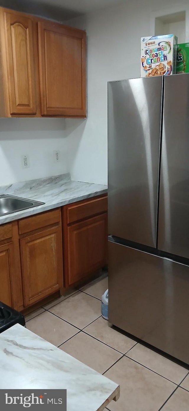 kitchen featuring light tile patterned floors, sink, and stainless steel refrigerator