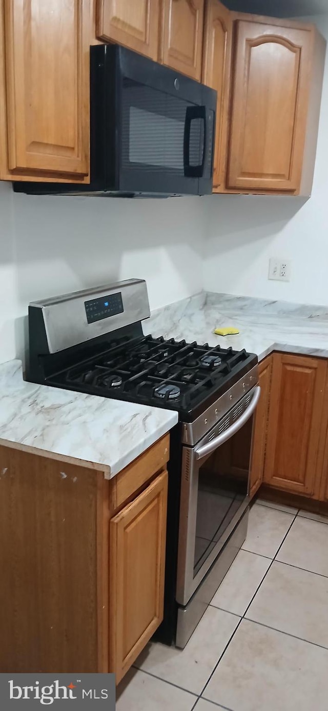 kitchen featuring light tile patterned floors and gas range