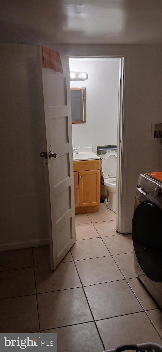 bathroom featuring toilet, tile patterned floors, washer / clothes dryer, and vanity