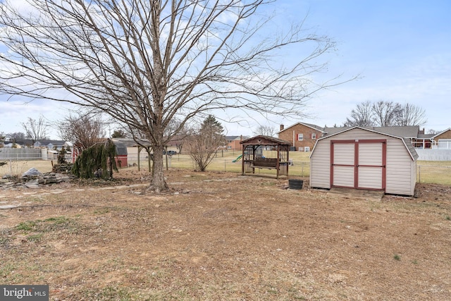 view of yard featuring a storage shed, fence, and an outbuilding