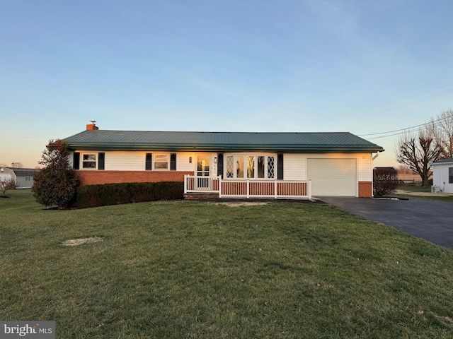 ranch-style house with a porch, a garage, and a yard