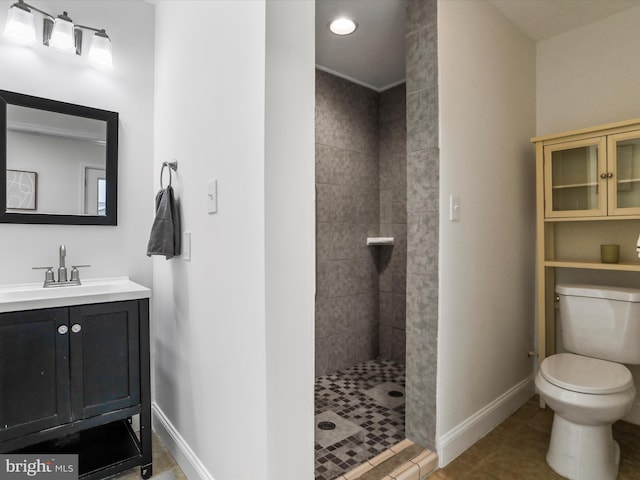 bathroom with tile patterned flooring, a tile shower, vanity, and toilet