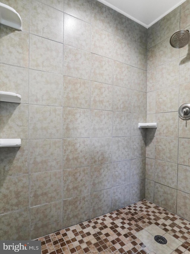 bathroom with ornamental molding and tiled shower