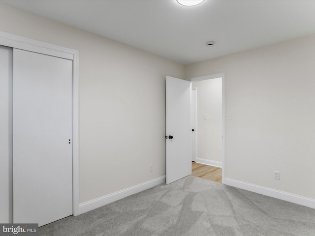 unfurnished bedroom with light colored carpet and a closet