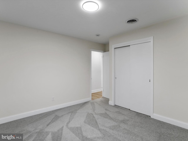 unfurnished bedroom featuring light carpet and a closet