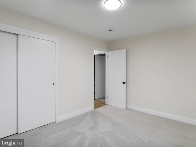 unfurnished bedroom with a closet and light colored carpet