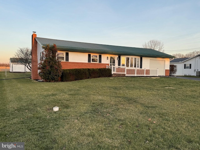 ranch-style house featuring covered porch, a garage, and a lawn