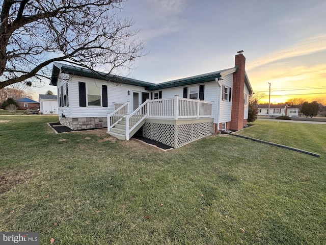 back house at dusk featuring a yard and a wooden deck