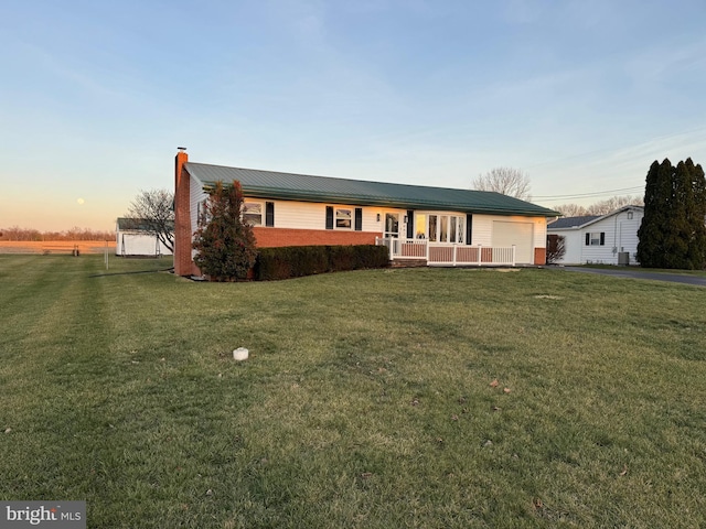 ranch-style home with covered porch and a yard