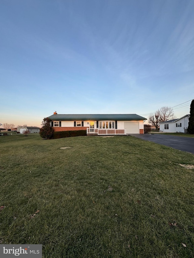 ranch-style house featuring a lawn, a porch, and a garage