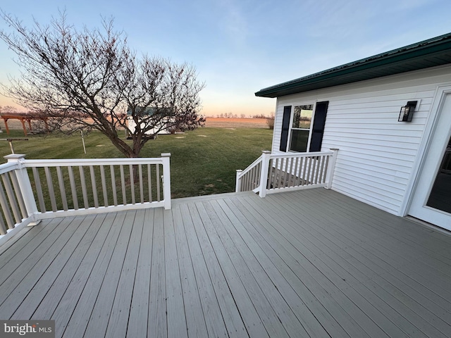 deck at dusk featuring a lawn