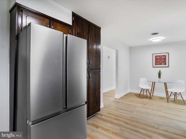 kitchen with stainless steel fridge, dark brown cabinets, and light hardwood / wood-style floors