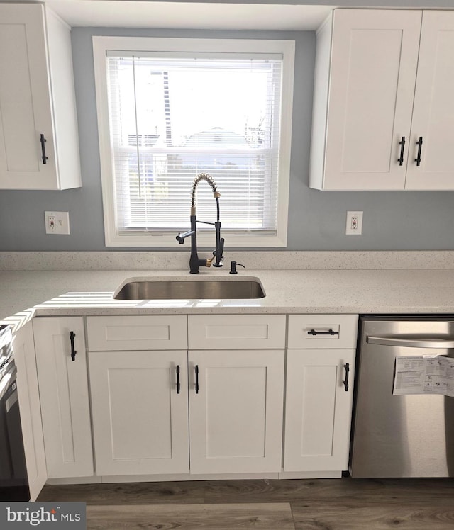 kitchen with dishwasher, white cabinetry, and sink