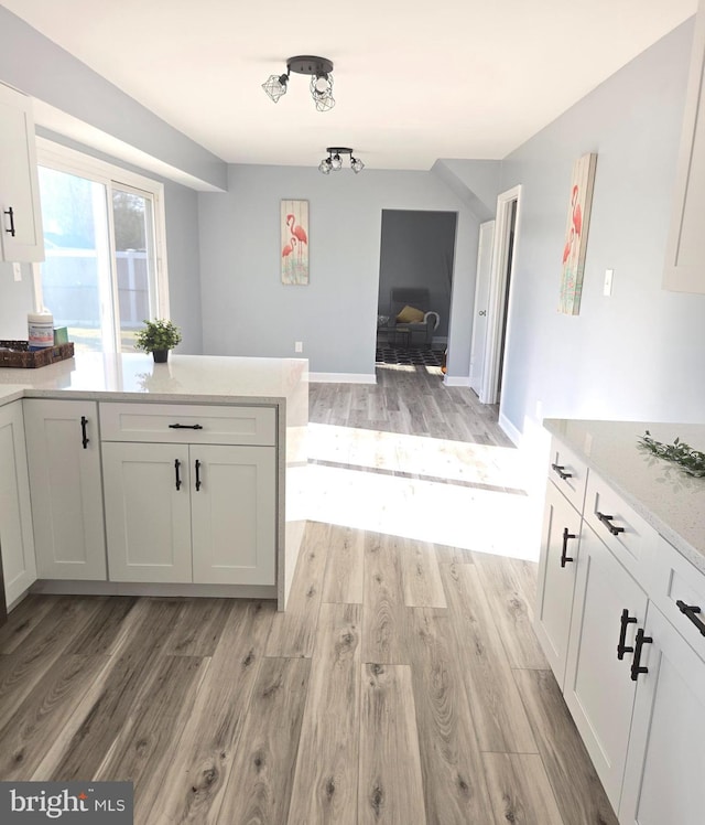 kitchen featuring light stone countertops, white cabinetry, and light hardwood / wood-style floors