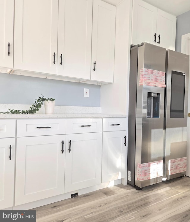 kitchen featuring stainless steel fridge with ice dispenser, white cabinetry, and light hardwood / wood-style flooring