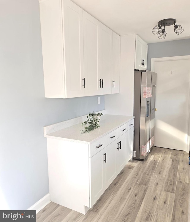 kitchen with light hardwood / wood-style flooring, white cabinets, and stainless steel refrigerator with ice dispenser