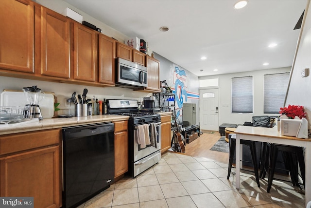 kitchen with tile counters, light tile patterned floors, and stainless steel appliances