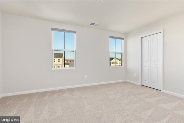 unfurnished bedroom with multiple windows, a closet, and light carpet