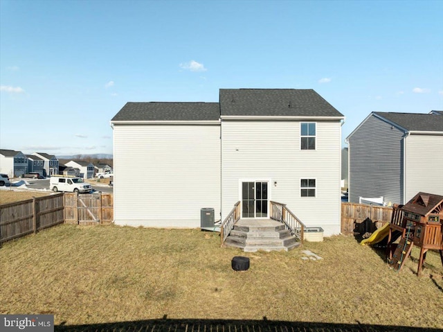 back of property featuring central AC, a yard, and a playground