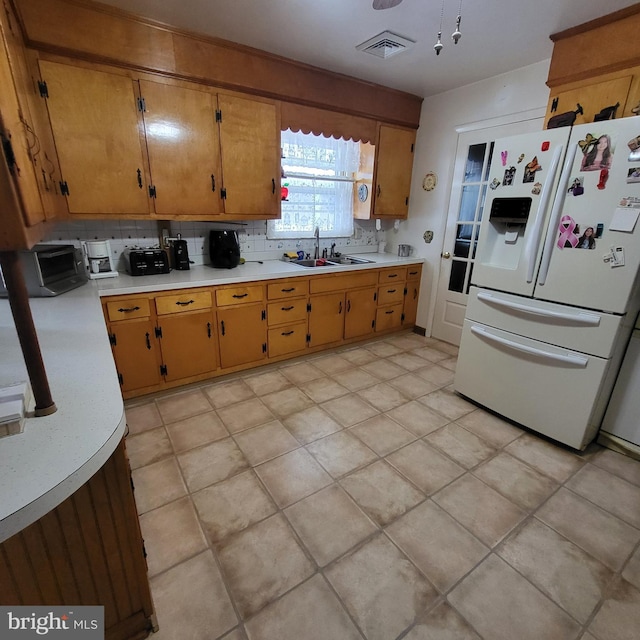 kitchen featuring decorative backsplash, sink, and white refrigerator with ice dispenser