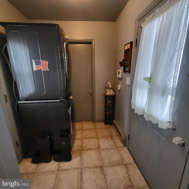 clothes washing area featuring stacked washer and dryer, a baseboard heating unit, and light tile patterned flooring