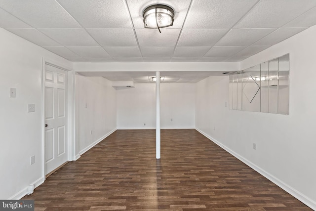 basement with a drop ceiling and dark wood-type flooring