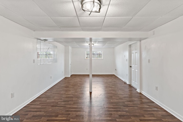 basement featuring a paneled ceiling and dark hardwood / wood-style flooring