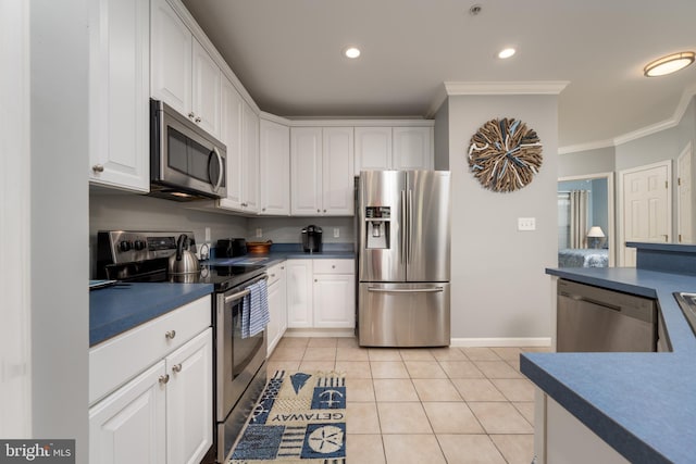 kitchen featuring white cabinetry, light tile patterned floors, stainless steel appliances, and ornamental molding