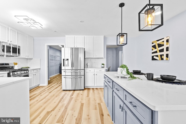 kitchen with hanging light fixtures, stainless steel appliances, tasteful backsplash, light hardwood / wood-style floors, and white cabinets