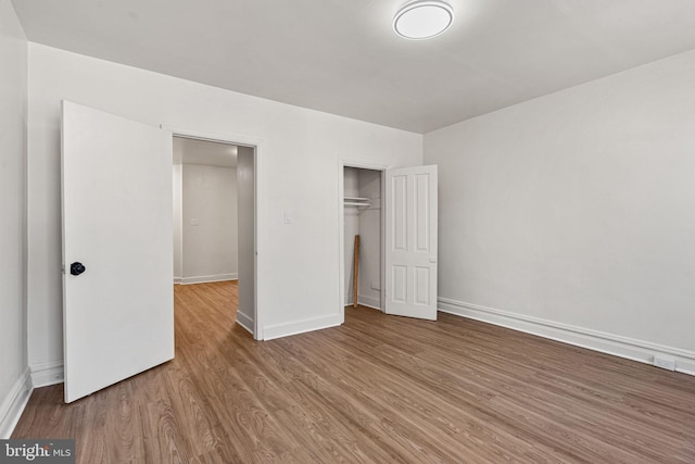 unfurnished bedroom featuring wood-type flooring and a closet