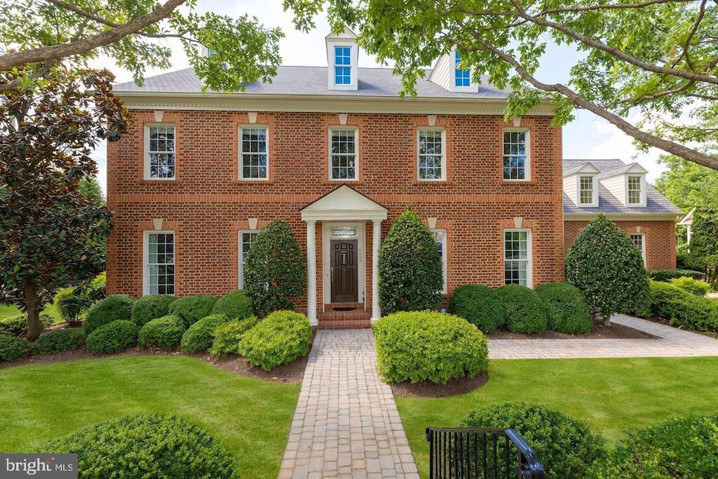 colonial home with brick siding and a front yard