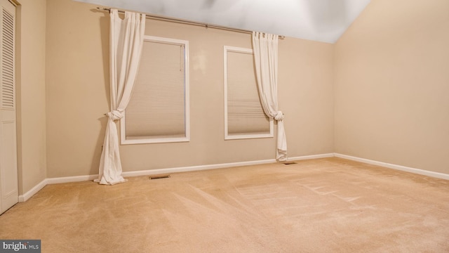 carpeted spare room featuring lofted ceiling