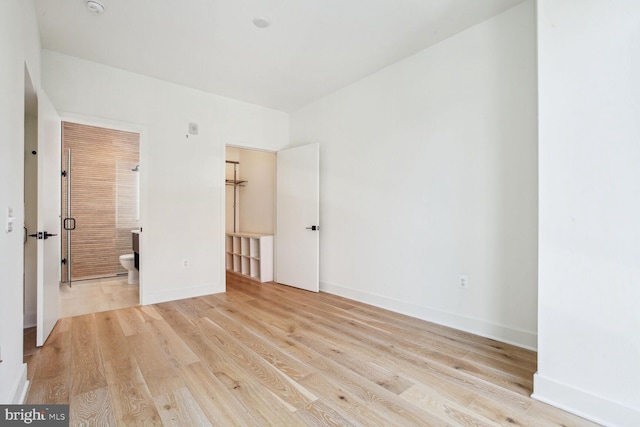 unfurnished bedroom featuring ensuite bathroom and light hardwood / wood-style flooring